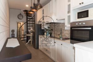 Kitchen with white cabinetry, oven, and spiral staircase at Villa Hingga