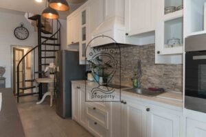 Kitchen with white cabinetry, oven, and spiral staircase at Villa Hingga