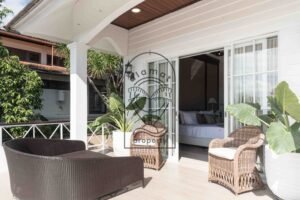 Covered terrace with rattan armchairs opening onto a bedroom at Villa Hingga