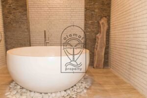 Bathroom with freestanding tub and stone-tiled walls at Villa Hingga