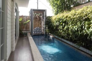 Private pool and pool deck with striped daybed cushions at Villa Hingga