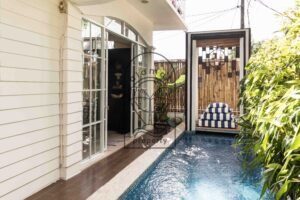 Private pool and pool deck with striped daybed cushions at Villa Hingga