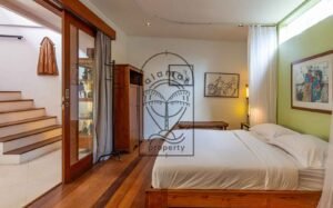 Villa Kaleidoscope bedroom with wooden bed frame and staircase view, Seminyak