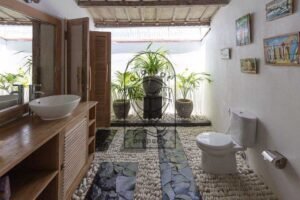 Villa Pachy bathroom with pebble floor, tropical plants and wooden vanity