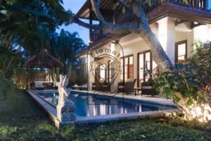 Villa exterior at dusk with private pool and garden statue at Villa Bugenvil