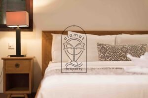 Bedside table with lamp and patterned cushions at Villa Bugenvil