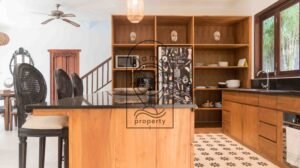Open kitchen with wooden shelving and tribal mask decor at Villa Bugenvil