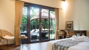Bedroom with garden view through wooden french doors at Villa Bugenvil