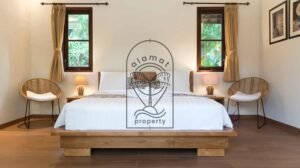 Bedroom with rattan armchairs and twin windows at Villa Bugenvil