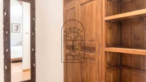 Carved wooden wardrobe and mirror in bedroom hallway at Villa Bugenvil