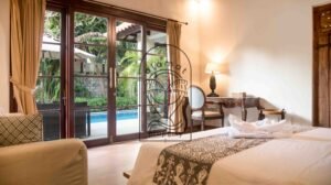 Bedroom with pool view through wooden french doors at Villa Bugenvil