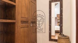 Carved wooden wardrobe and tall mirror in bedroom at Villa Bugenvil