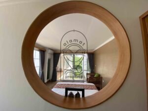 Bright bedroom with round mirror and rustic wood bed at Villa Ramaia
