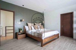 Bedroom with green accent wall and wooden bed at Villa Aruna Sari