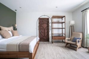 Bedroom with open wood shelving and armchair at Villa Aruna Sari