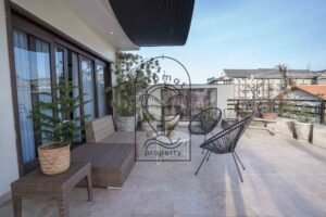 Rooftop terrace lounge with rattan sofa and potted plants at Villa Aruna Sari