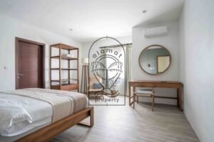Bedroom with round mirror, desk, and reading chair at Villa Aruna Sari