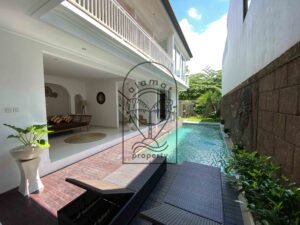 Poolside deck with sun loungers and tropical plants at Villa Ramaia