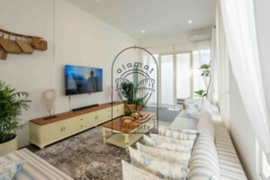 Living room with TV, cream sideboard and floral cushions in a 6-bedroom villa for rent in Berawa
