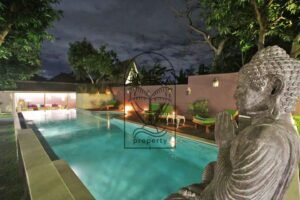 Villa Mizu swimming pool at night with Buddha statue and sun loungers