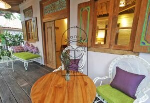 Villa Mizu veranda with teak table, wrought iron chairs and carved shutters