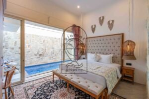 Bedroom with tufted headboard, bench and private pool view at Villa Jendaya