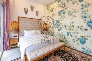 Bedroom with blue floral wallpaper, rattan lamps and Persian-style rug