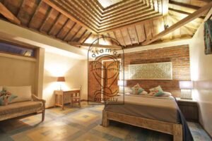 Villa Mizu bedroom with brick wall, daybed and carved ceiling