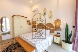 Bedroom with rattan headboard, cream wardrobe and cactus at Villa Jendaya
