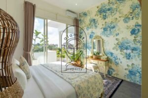 Blue floral wallpaper, dressing table and balcony doors in a Berawa villa bedroom