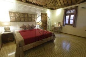 Villa Mizu bedroom with red bedspread and carved headboard