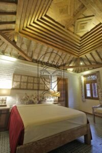 Villa Mizu bedroom with carved teak ceiling and floral cushions